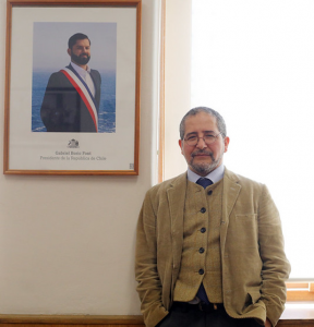 Director del INH, Emilio Torres Valdebenito, de pie, con la fotografía del Presidente Gabriel Boric al fondo, al lado izquierdo desde la vista del usuario.