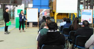 Experto en Prevención de Riesgos, Sabrina Rivera, se dirige a los presentes, mientras se encuentra de pie, con el micrófono en la mano, acompañada por el Presidente del Comité Paritario.