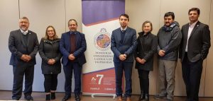 Grupo de personas de frente, con el pendón de la universidad detrás.