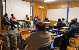 Cuatro mujeres profesionales sentadas en el panel frente a las y los estudiantes.