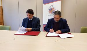 Las dos autoridades, sentadas, firmando los documentos.