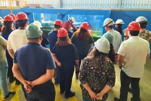 Persona muestra canal de olas a integrantes del comité de pie frente al canal.