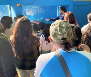 Ingeniero INH explica cómo funciona el canal de olas, que contiene agua simulando oleaje contra un rompeolas.