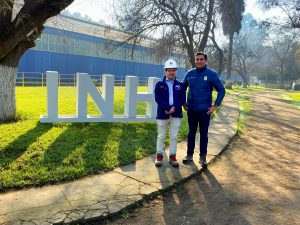 Director del INH y alcalde de Peñaflor de pie junto a letras volumétricas INH, con el laboratorio de fondo.