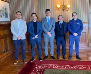 Asistentes a la firma del convenio de pie, mirando al frente.