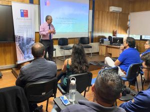 Director del INH está de pie, hablando a las personas sentadas en la sala.